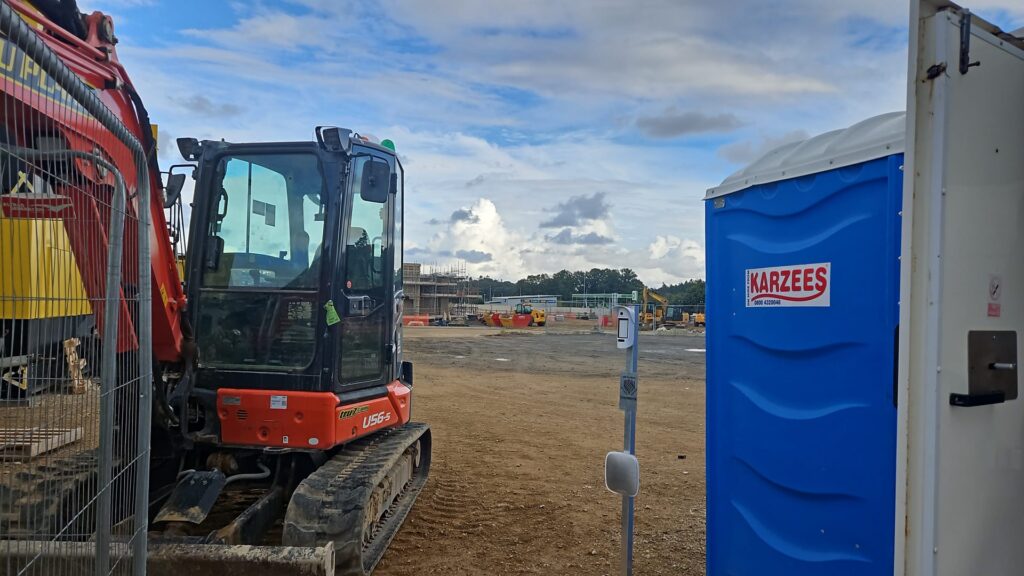 Temporary Ajax alarm system protecting site cabin on active construction site in Cambridgeshire with plant machinery and groundworks in progress.