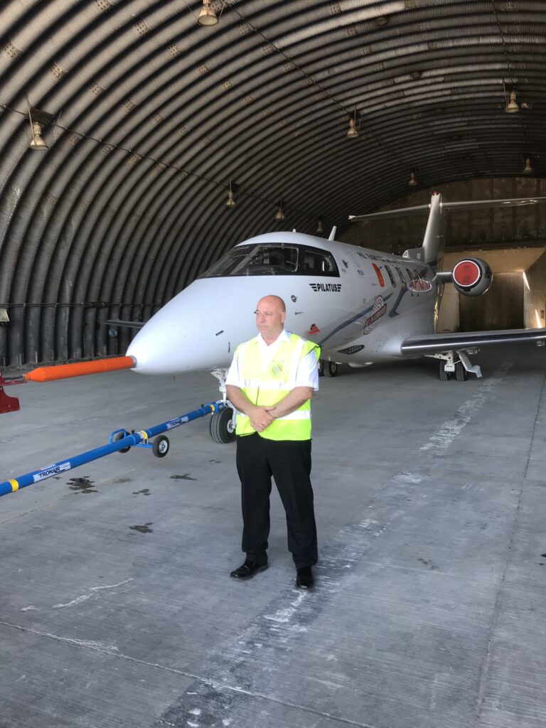 Aviation security officer beside aircraft in hangar during specialist testing operations