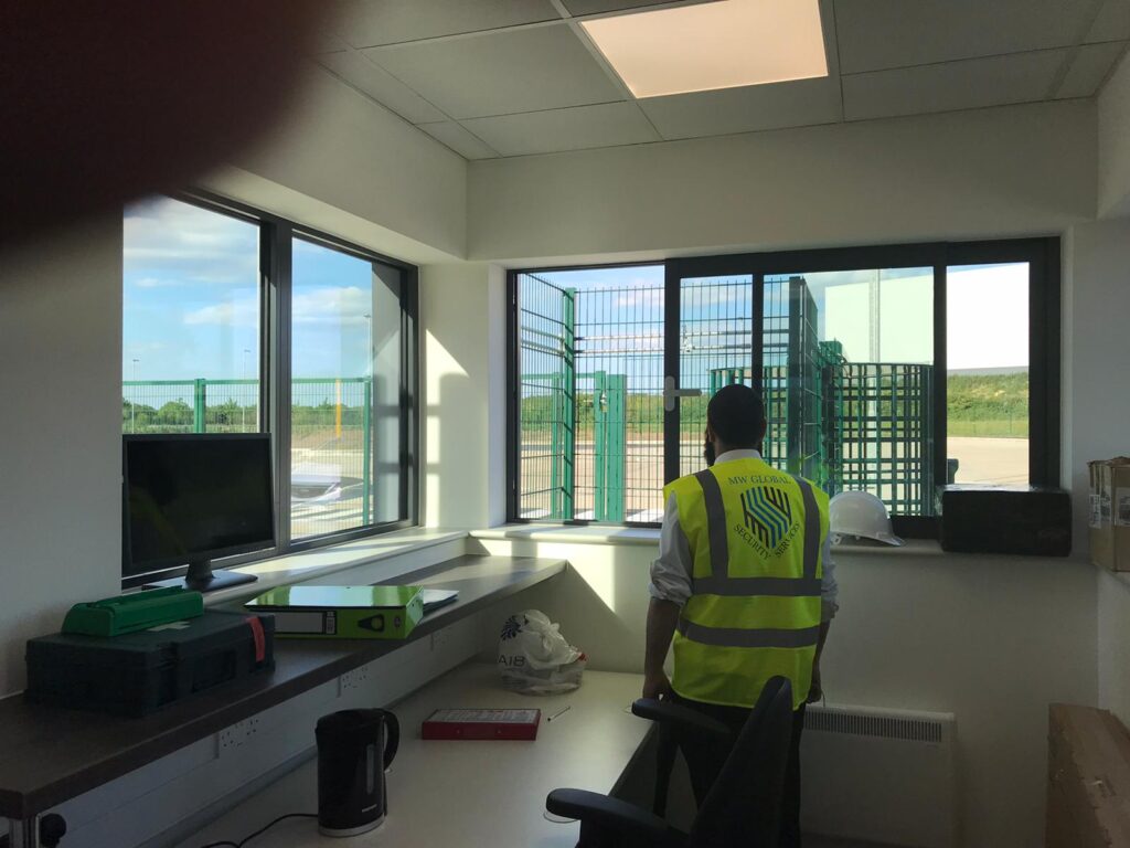 Gatehouse security officer monitoring secure site access from inside gatehouse control room