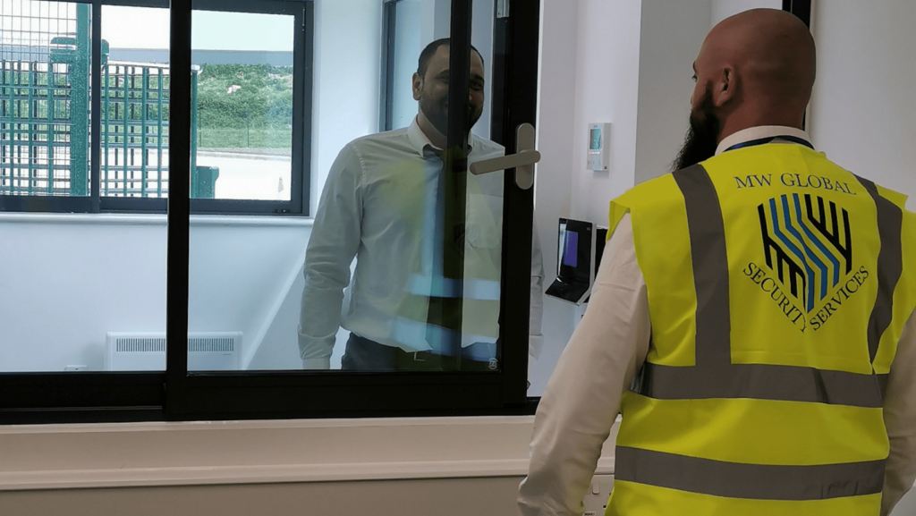 Gatehouse security officer assisting visitor at secure access hatch and check in point